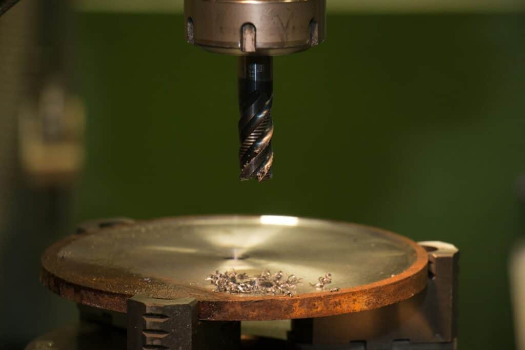 Stainless steel drill bit about to reach the bottom of a hole, illustrating precise powered tapping work